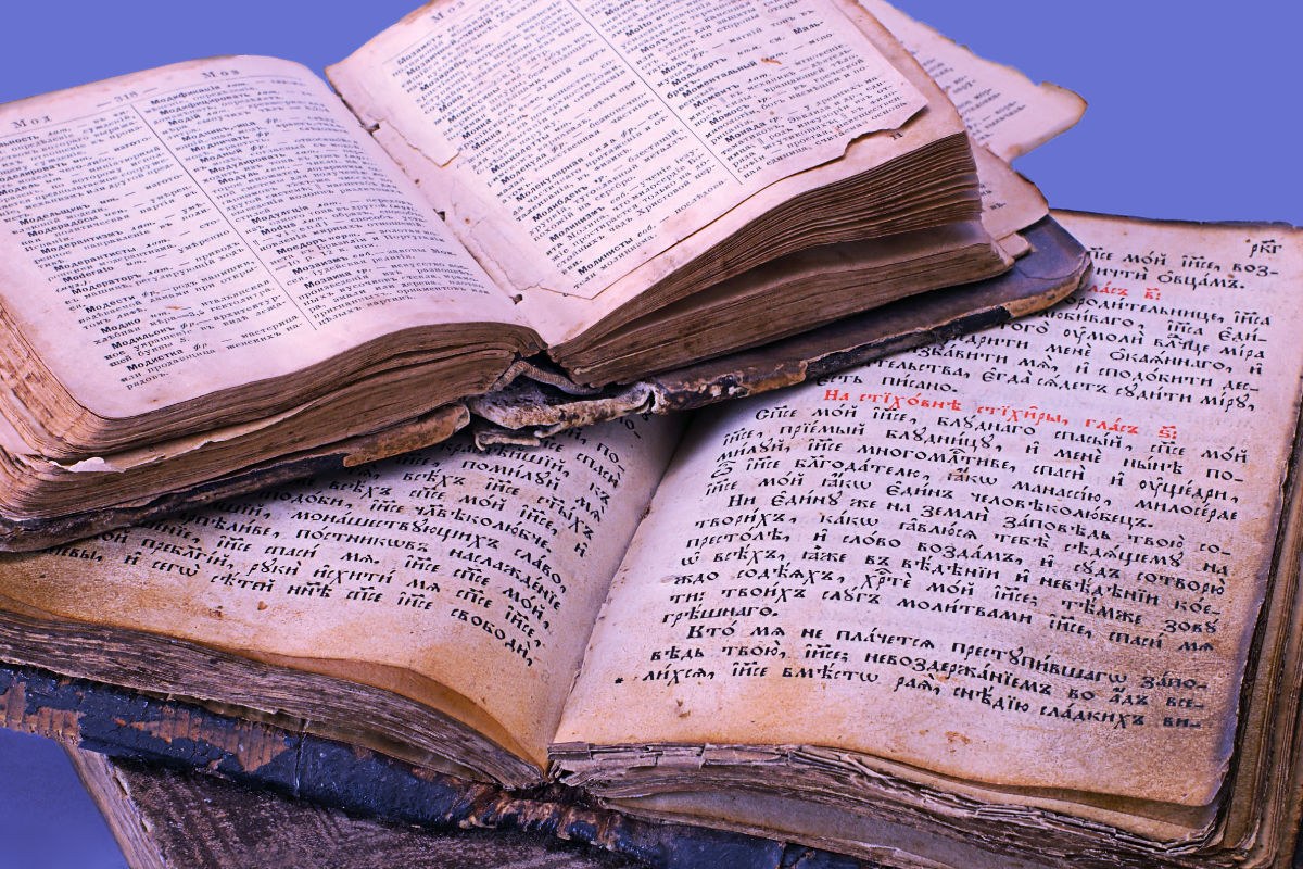 Zwei alte Bücher mit vergilbten Seiten liegen aufgeschlagen übereinander.