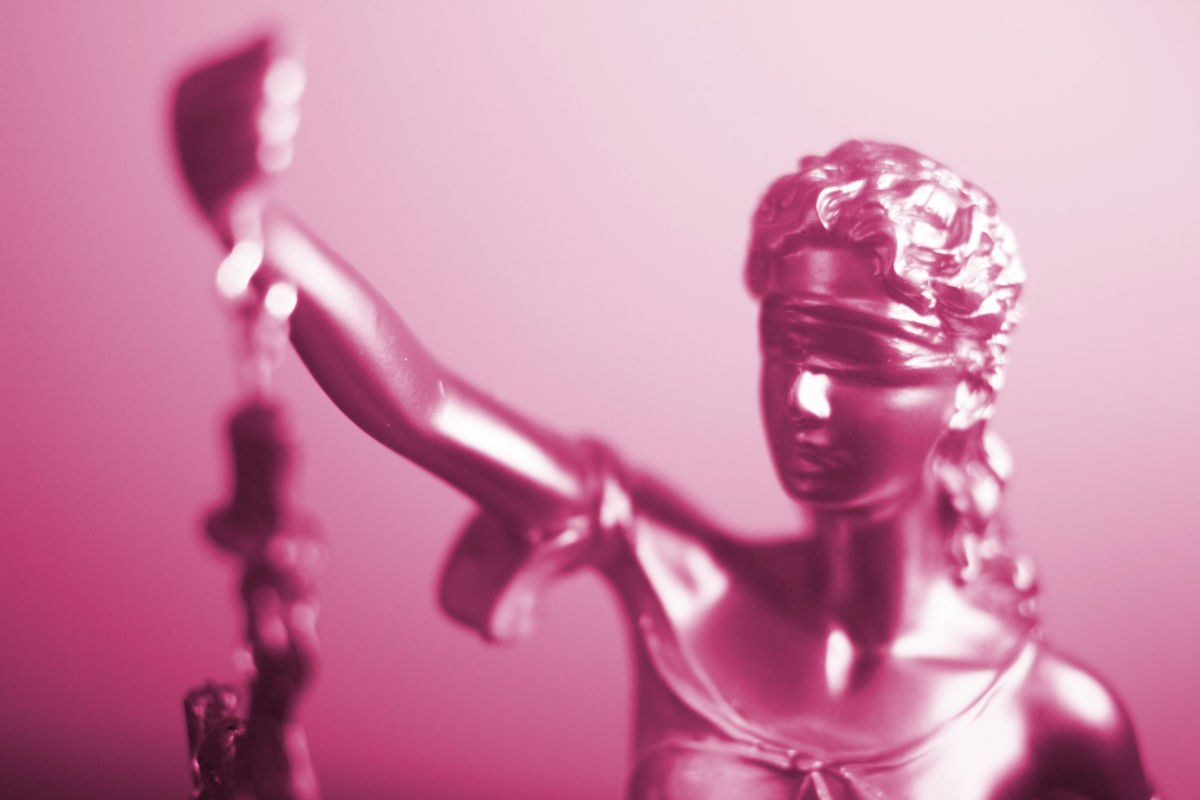 Es ist ein Portrait von Justitia zu sehen, welches aufgrund der Beleuchtung rötlich erscheint.